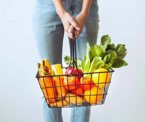 A person holds a basket full of vegetables
